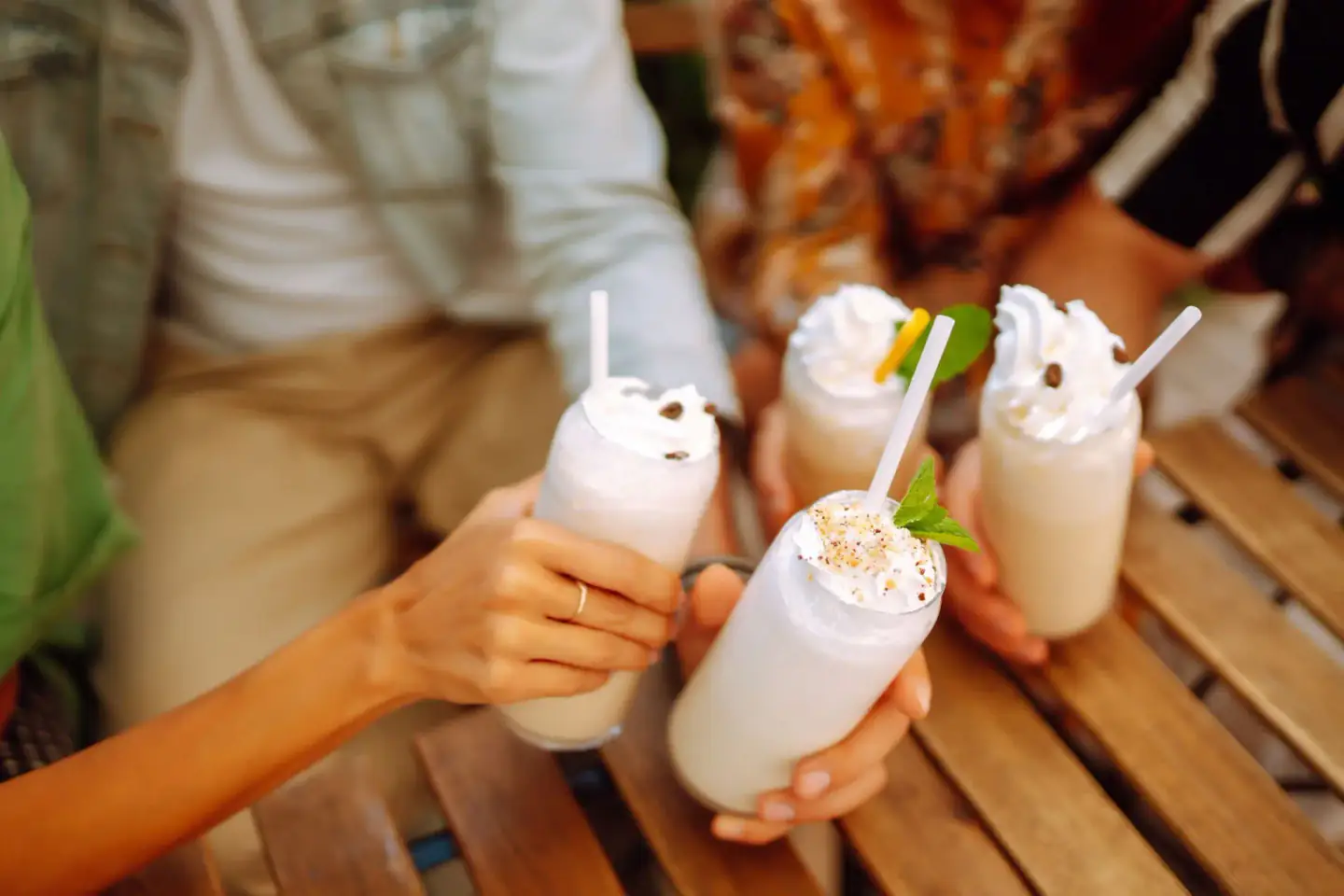 Friends toasting creamy milkshakes topped with whipped cream