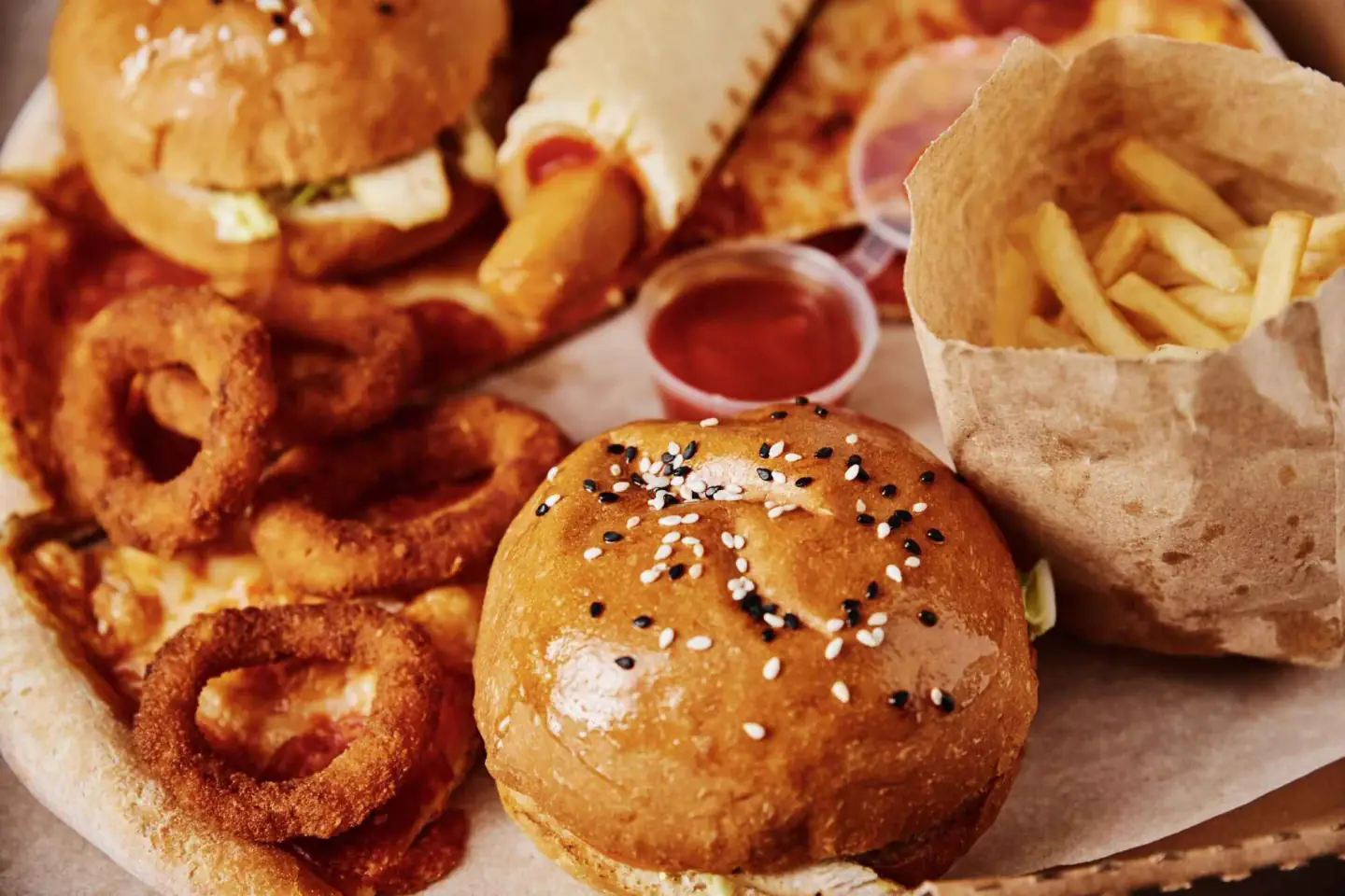 Black Burger platter with sesame bun burger, onion rings, fries