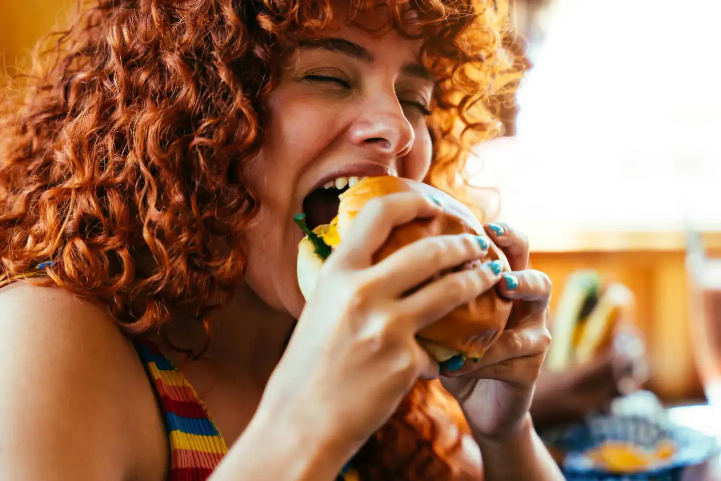 Woman joyfully biting a juicy hamburger for Black Burger
